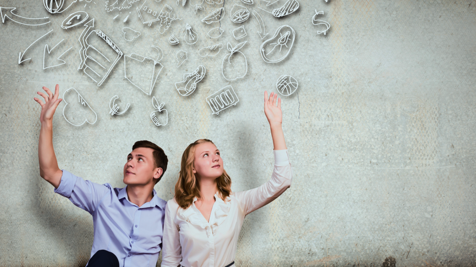 Couple sitting on floor with their arms raised and hand drawn images of their dreams behind them 