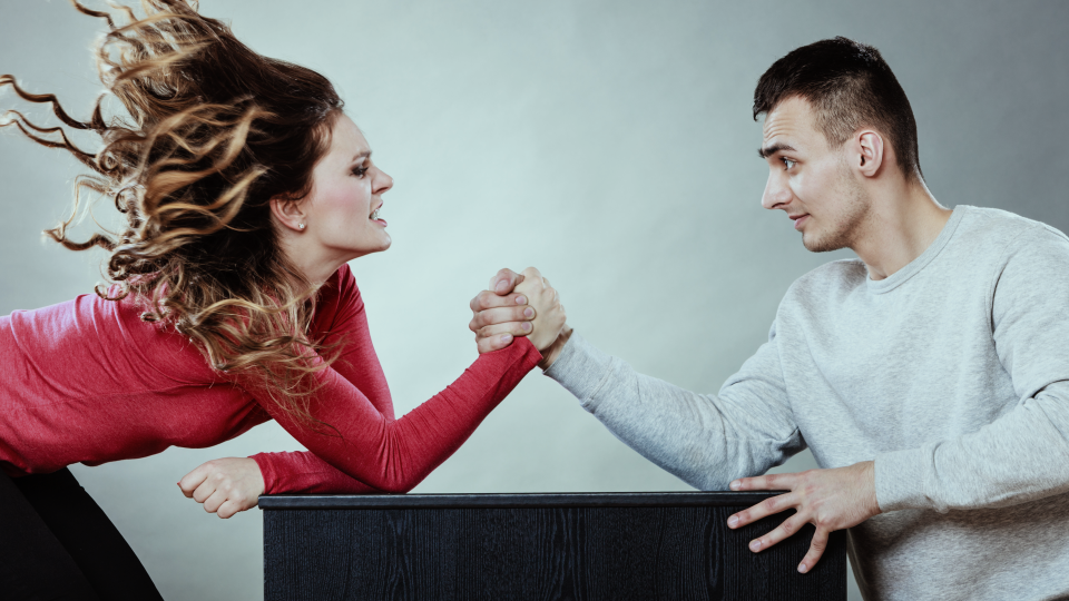 Woman in fiery red top and wild hair arm wrestling  