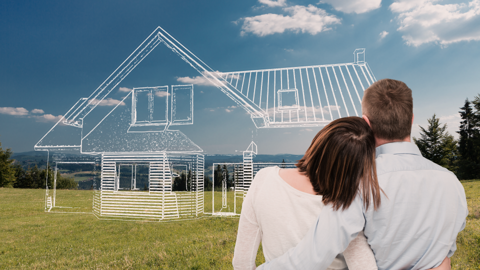 Couple hugging each other infront of a hilltop vista with a hand drawn house sketch where a house could be built